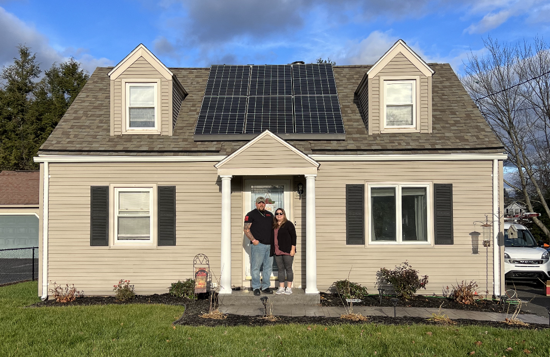 Family outside of house with solar panels